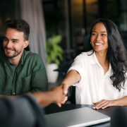 Handshake of happy young business woman and business man at office meeting. Female hr bank manager, financial advisor handshaking recruit, greeting client. Hiring at job interview, partnership concept